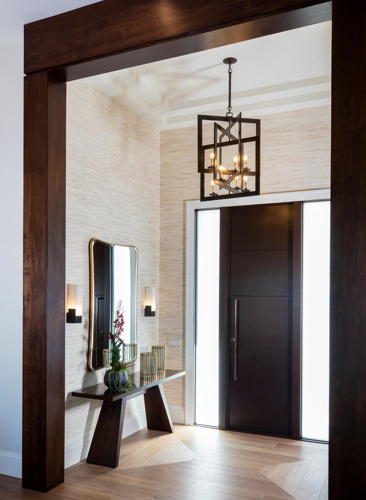 Example of a mid-sized minimalist medium tone wood floor and brown floor entryway design in Miami with beige walls and a dark wood front door
