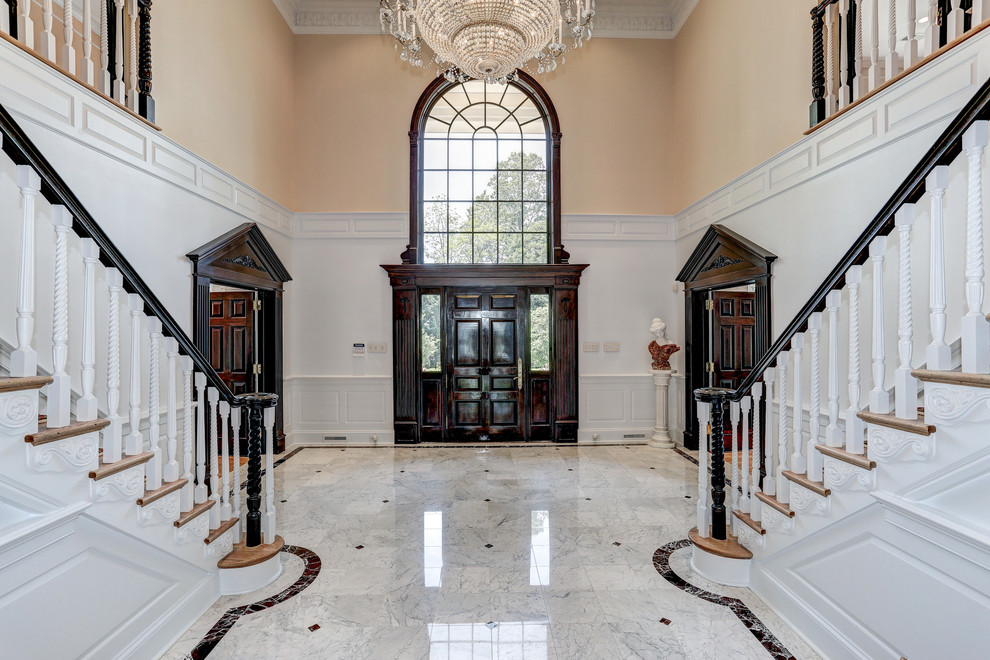 ワシントンD.C.にあるラグジュアリーな巨大なトラディショナルスタイルのおしゃれな玄関ロビー (白い壁、大理石の床、濃色木目調のドア) の写真