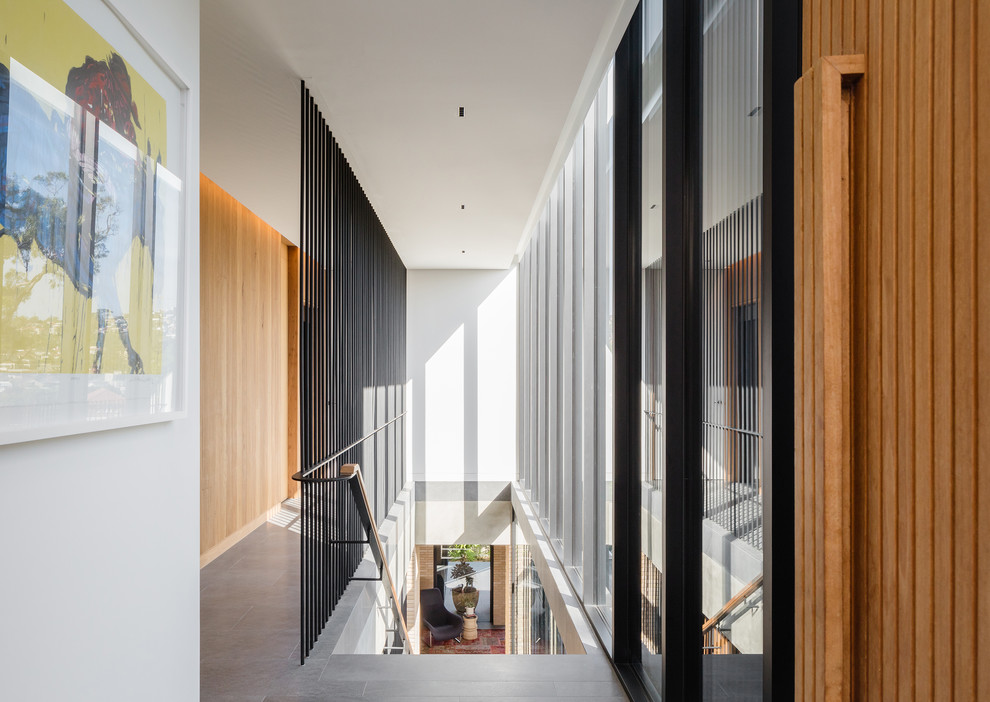 Aménagement d'une grande entrée moderne avec un couloir et un sol gris.