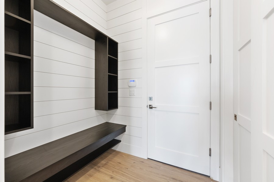 Aménagement d'une entrée contemporaine de taille moyenne avec un vestiaire, un mur blanc, parquet clair, une porte simple, une porte blanche et un sol marron.