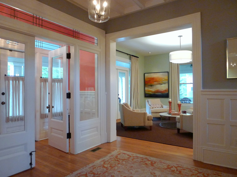 Foto di un grande ingresso classico con pareti arancioni, pavimento in legno massello medio, una porta a due ante e una porta bianca