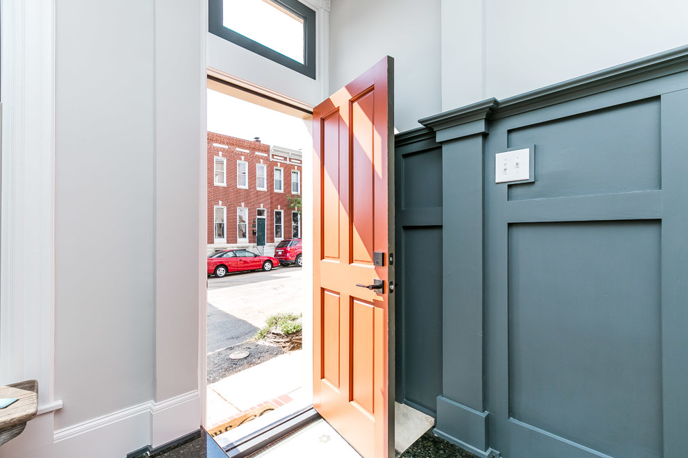 Lantlig inredning av en mellanstor ingång och ytterdörr, med vita väggar, mellanmörkt trägolv, en enkeldörr och en orange dörr