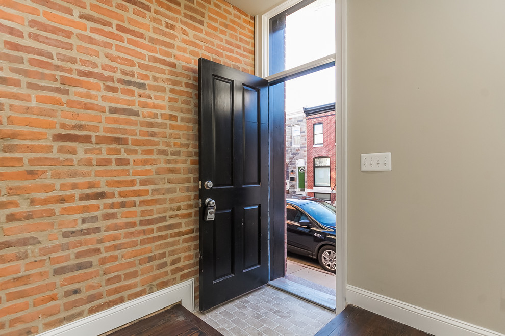На фото: входная дверь среднего размера в стиле неоклассика (современная классика) с бежевыми стенами, кирпичным полом, одностворчатой входной дверью и черной входной дверью с