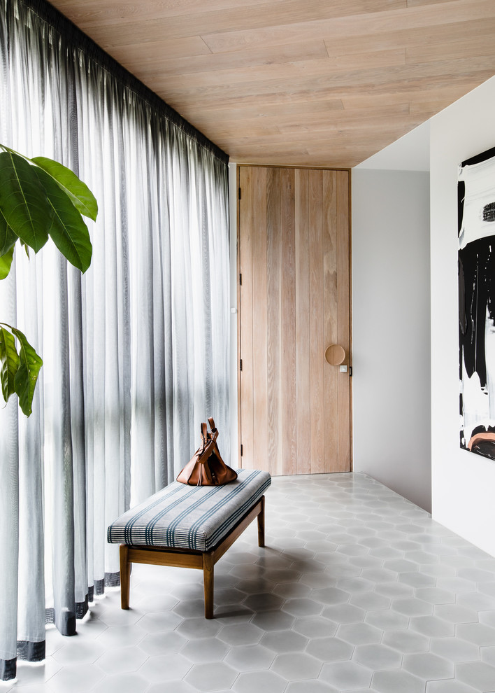 На фото: фойе в современном стиле с белыми стенами, полом из керамической плитки, одностворчатой входной дверью, входной дверью из светлого дерева и серым полом