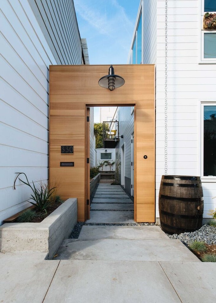 Esempio di un ingresso con vestibolo minimalista di medie dimensioni con pareti bianche, pavimento in cemento, una porta singola e una porta in legno bruno