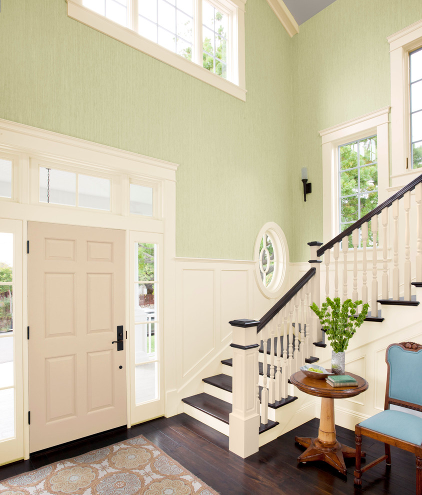 Cette image montre un grand hall d'entrée traditionnel avec un mur vert, parquet foncé, une porte simple et une porte blanche.