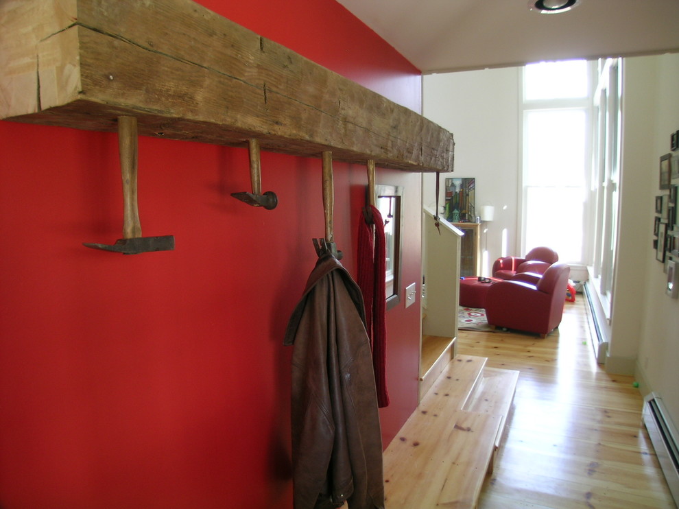 Réalisation d'une entrée champêtre avec un vestiaire, un mur rouge et parquet clair.