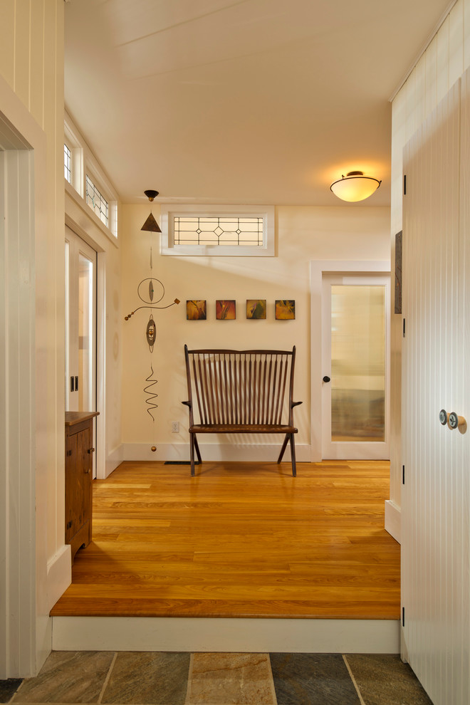 Aménagement d'une entrée campagne avec un couloir, un mur beige et un sol en bois brun.