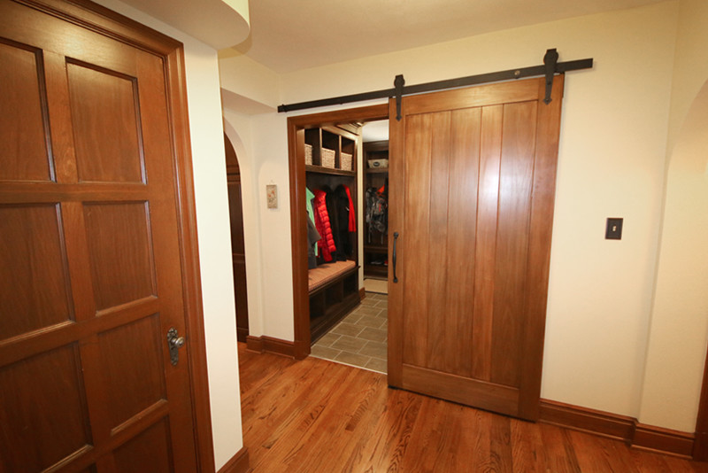This is an example of a small contemporary boot room in St Louis with brown walls, light hardwood flooring, a single front door, a medium wood front door and brown floors.