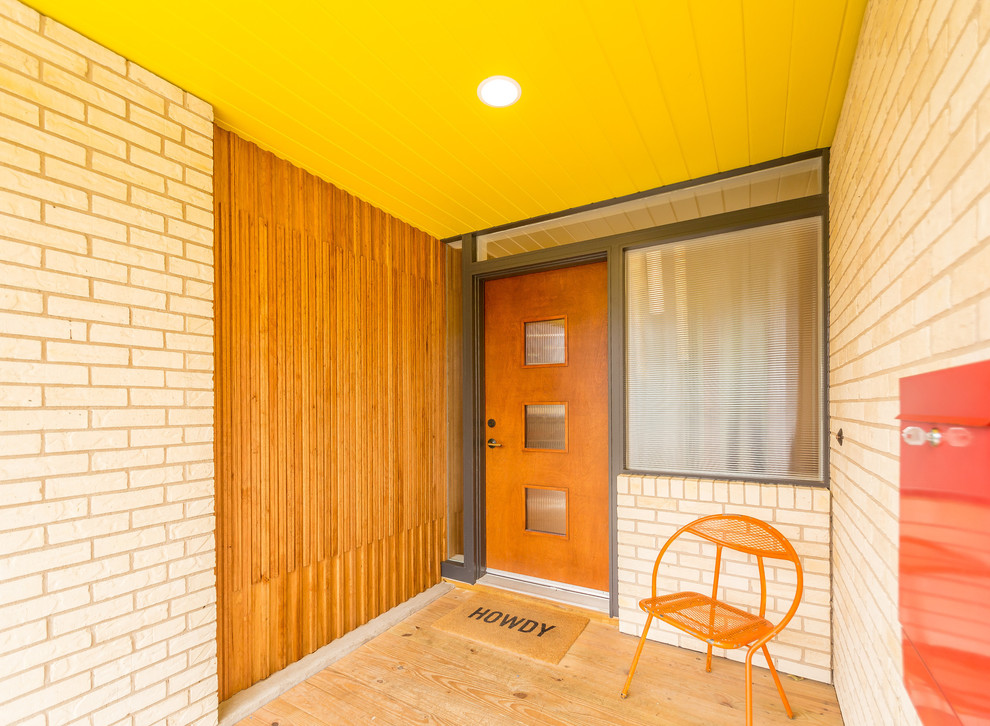 Immagine di una porta d'ingresso minimalista di medie dimensioni con pareti multicolore, pavimento in compensato, una porta singola e una porta in legno bruno