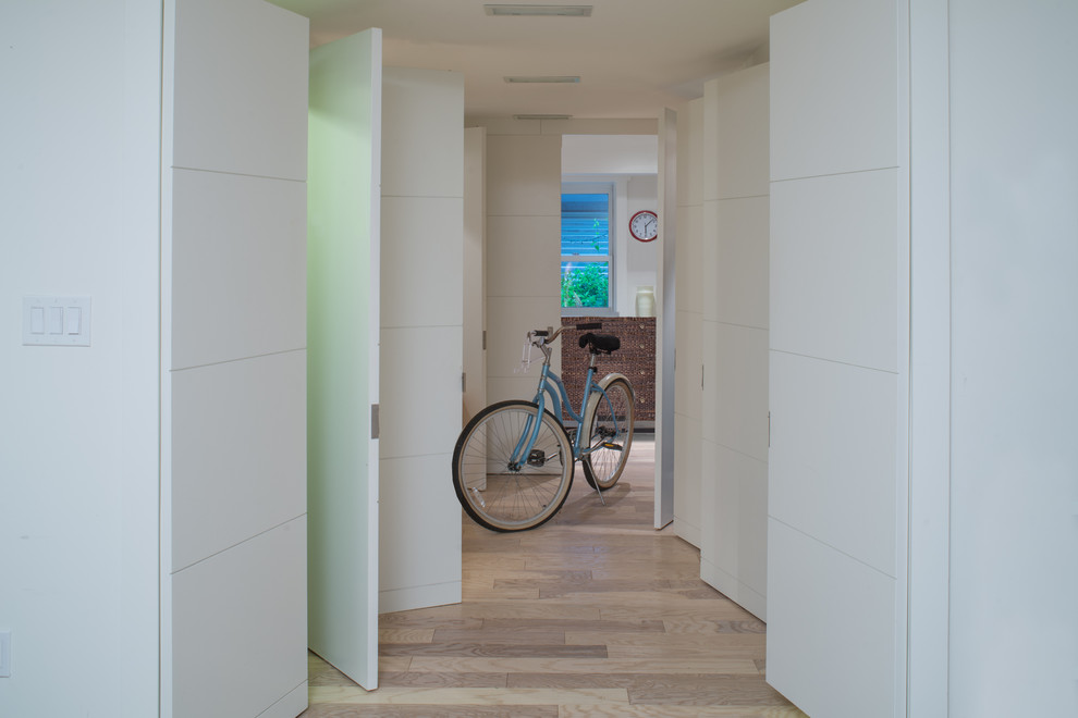 Cette photo montre une entrée tendance avec un couloir, un mur blanc et parquet clair.