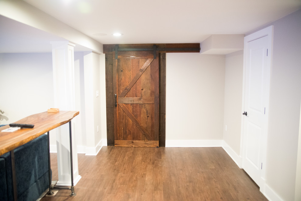 Cette image montre une entrée chalet de taille moyenne avec un couloir, un mur gris, un sol en bois brun, une porte simple et une porte en bois foncé.