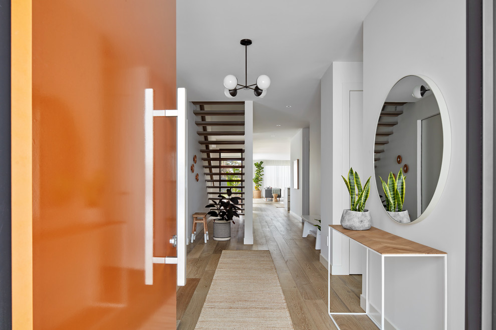 Ejemplo de hall actual con paredes blancas, puerta simple, puerta naranja, suelo marrón y suelo de madera clara