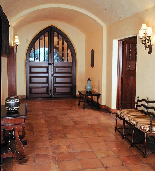 Aménagement d'une grande porte d'entrée méditerranéenne avec un mur beige, tomettes au sol, une porte double, une porte en bois foncé et un sol marron.