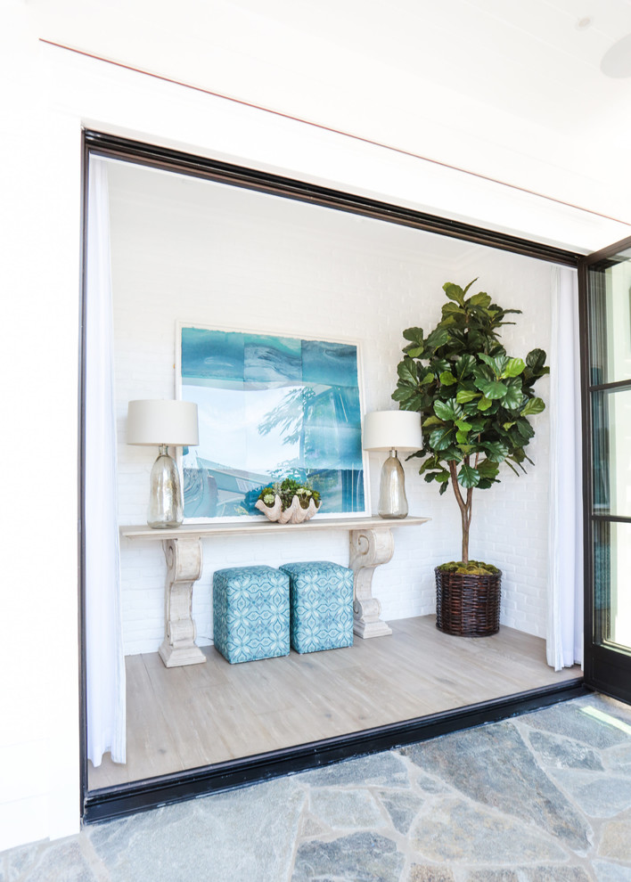 Example of a small beach style light wood floor entryway design in Orange County with white walls