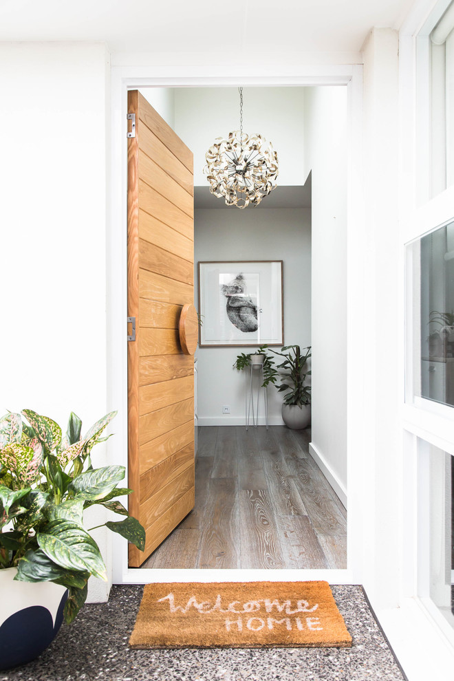 Diseño de entrada nórdica con paredes blancas, puerta simple y puerta de madera clara