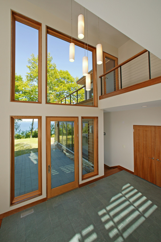 Diseño de puerta principal moderna de tamaño medio con paredes blancas, suelo de pizarra, puerta simple, puerta de vidrio y suelo verde