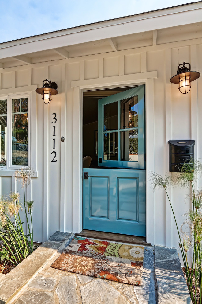 Mid-sized beach style limestone floor entryway photo in Los Angeles with a blue front door and white walls