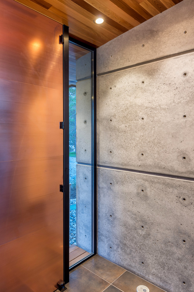 Foto på en liten funkis foajé, med grå väggar, klinkergolv i porslin, en pivotdörr, en orange dörr och beiget golv