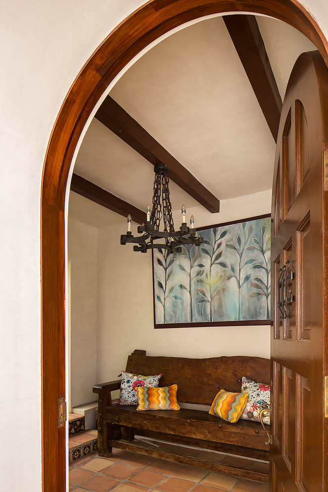 Aménagement d'une entrée méditerranéenne de taille moyenne avec un vestiaire, un mur beige, tomettes au sol, une porte simple et une porte en bois foncé.