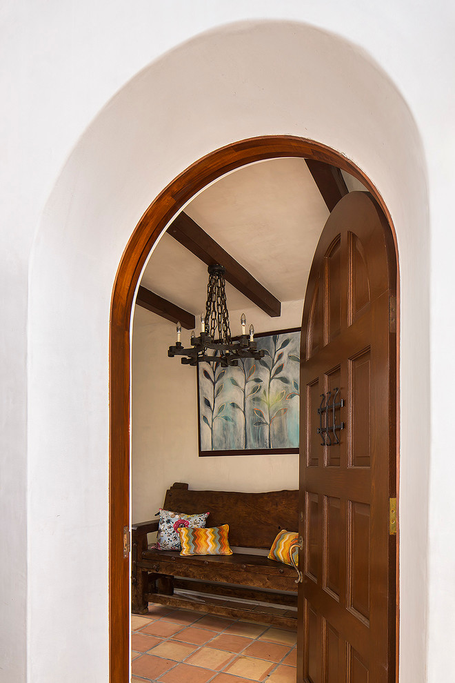 Idée de décoration pour une entrée méditerranéenne de taille moyenne avec un vestiaire, un mur beige, tomettes au sol, une porte simple et une porte en bois foncé.