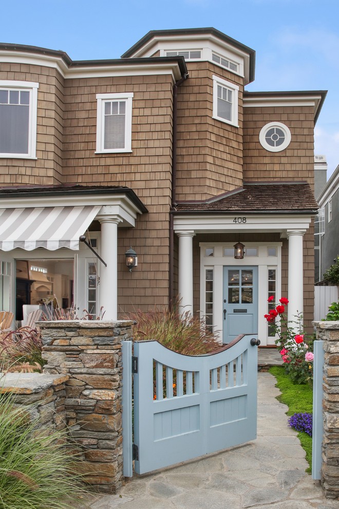 Стильный дизайн: прихожая в морском стиле с коричневыми стенами, одностворчатой входной дверью и синей входной дверью - последний тренд