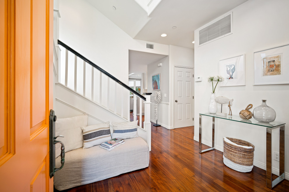 Maritimer Eingang mit weißer Wandfarbe, dunklem Holzboden, Einzeltür, oranger Haustür und braunem Boden in Los Angeles