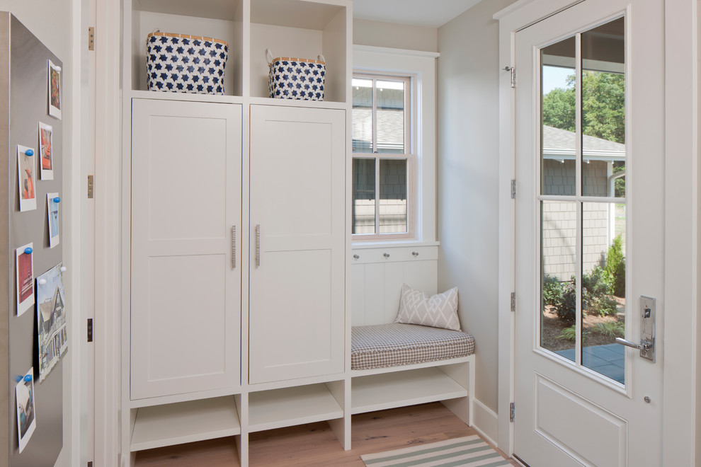 Aménagement d'une petite porte d'entrée classique avec un mur beige, parquet clair, une porte simple, une porte blanche et un sol marron.
