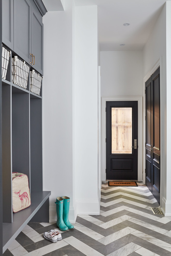 Cette image montre une entrée traditionnelle avec un vestiaire, un mur blanc, un sol en carrelage de porcelaine, une porte simple, une porte grise et un sol gris.
