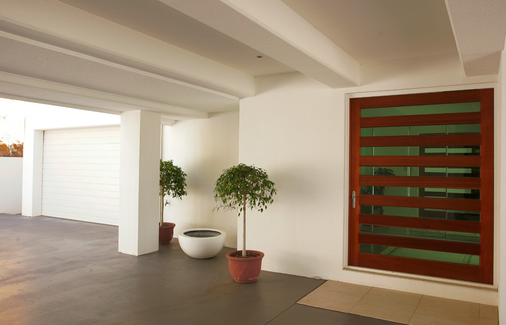 Cette image montre une porte d'entrée minimaliste avec un mur blanc, une porte simple et une porte en bois brun.