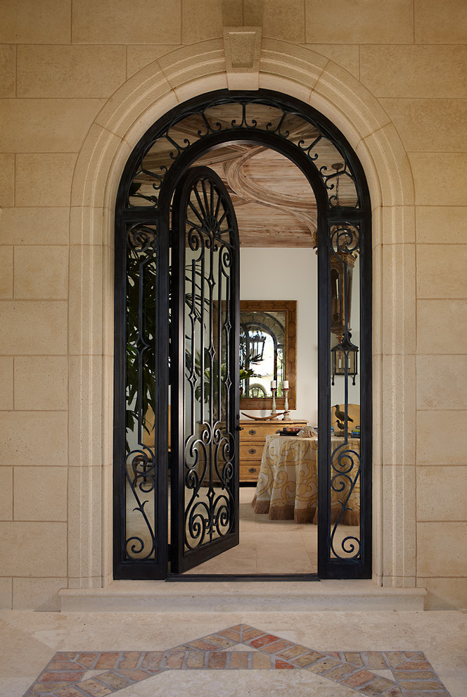 На фото: входная дверь в средиземноморском стиле с бежевыми стенами, одностворчатой входной дверью и черной входной дверью с