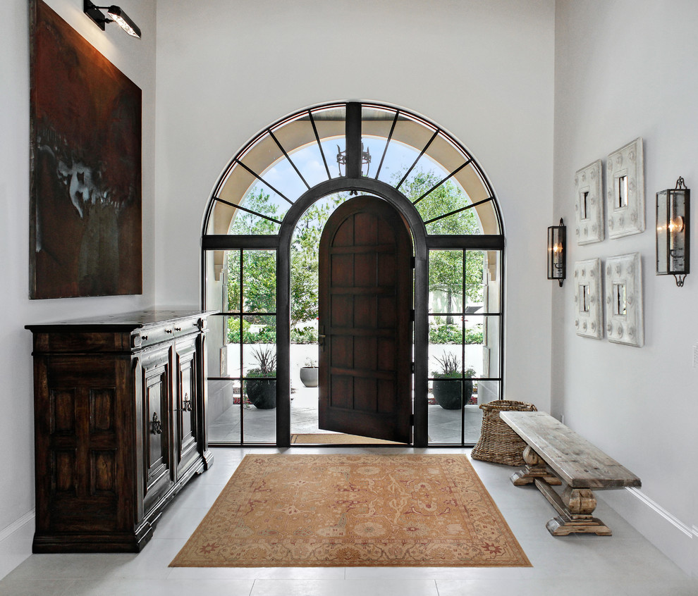 Photo of a mediterranean foyer in Miami with white walls, a single front door and a dark wood front door.