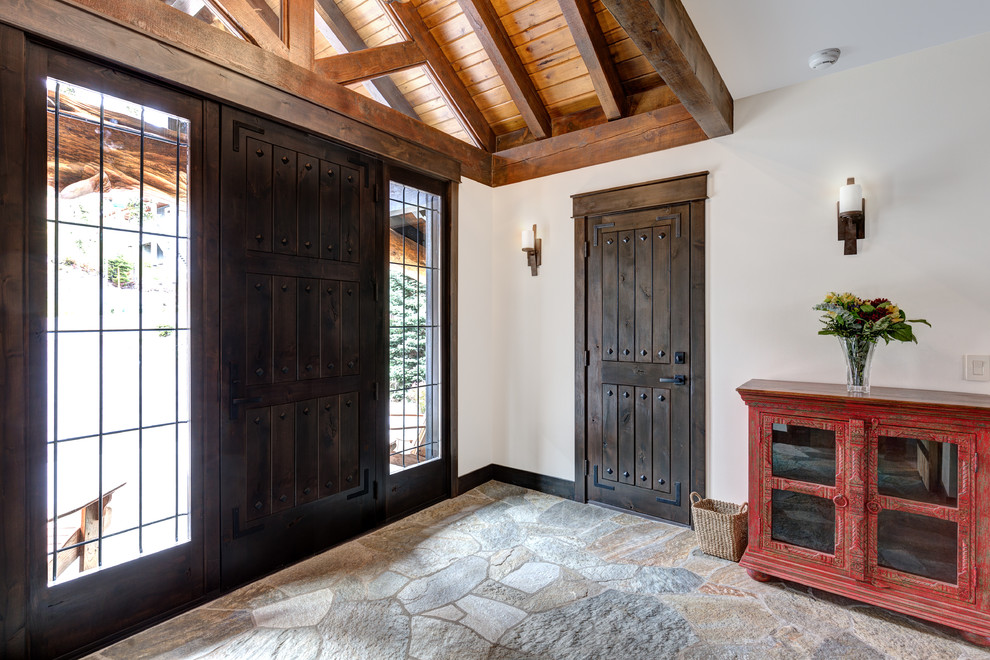 Esempio di un ingresso o corridoio stile rurale con pareti bianche, pavimento in ardesia, una porta singola e una porta in legno scuro