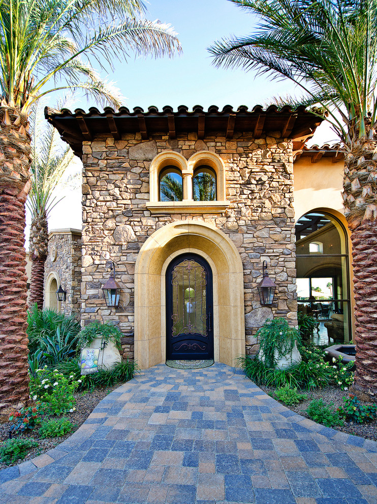 На фото: большая входная дверь в средиземноморском стиле с одностворчатой входной дверью и стеклянной входной дверью