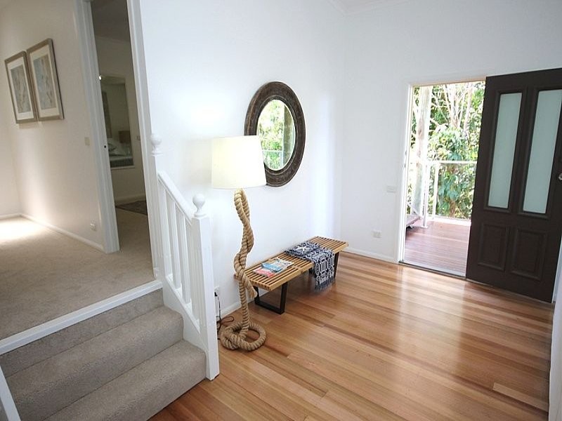 Small beach style light wood floor entryway photo in Other with white walls and a black front door