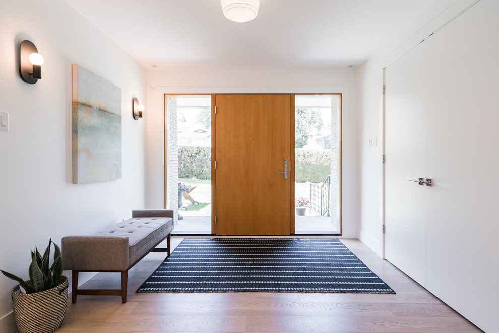 Modernes Foyer mit weißer Wandfarbe, braunem Holzboden, Einzeltür, hellbrauner Holzhaustür und braunem Boden in Vancouver