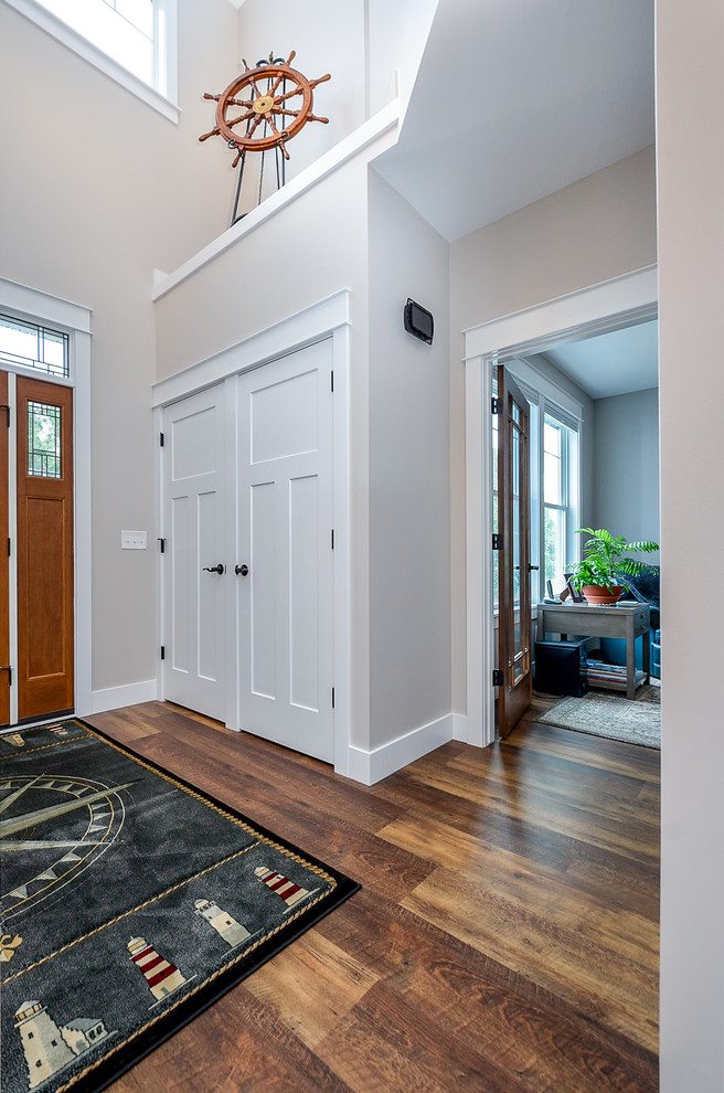 他の地域にある中くらいなコンテンポラリースタイルのおしゃれな玄関ロビー (ベージュの壁、無垢フローリング、木目調のドア、茶色い床) の写真