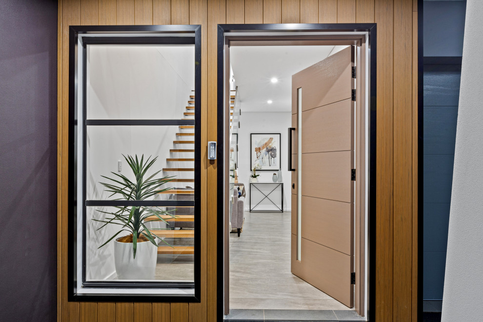 Idée de décoration pour une grande entrée design avec un mur blanc, un sol en carrelage de céramique, une porte double, une porte en bois brun et un sol gris.