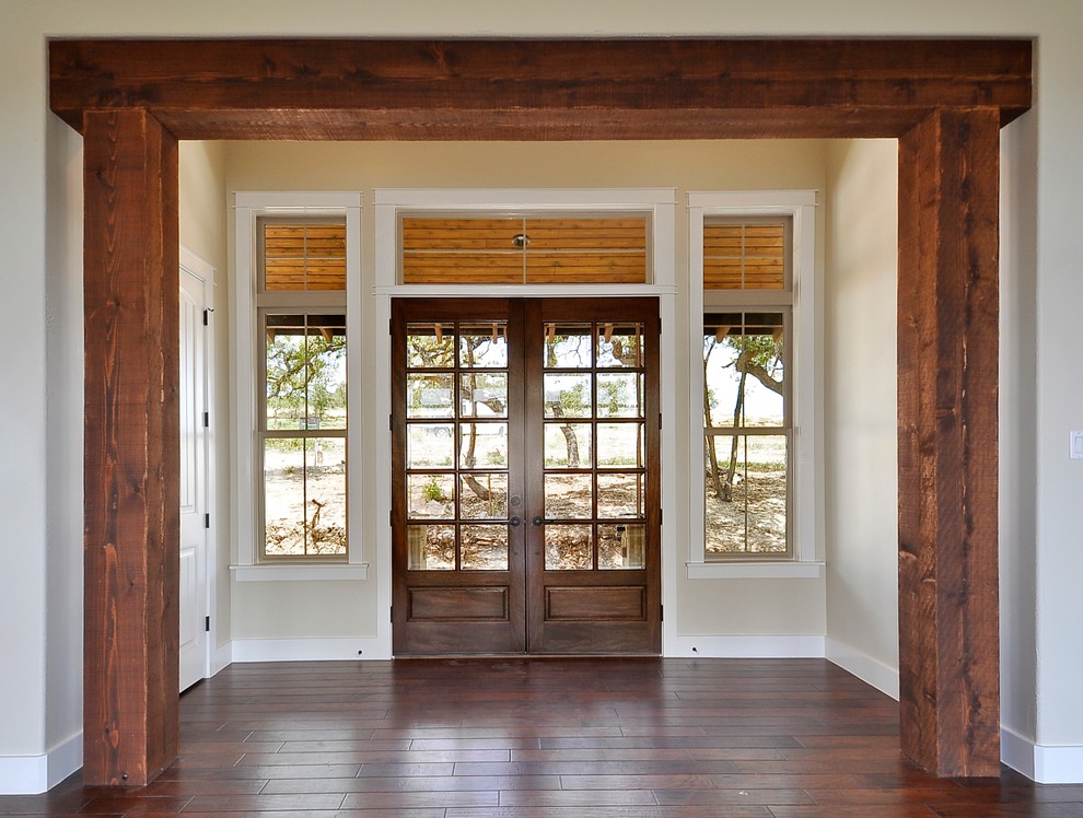 Cette image montre une entrée sud-ouest américain avec un mur beige, une porte double et une porte en bois foncé.