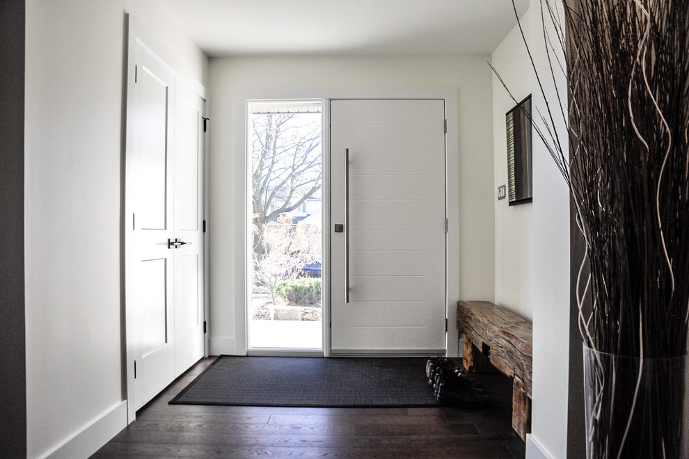 Exempel på en mellanstor klassisk foajé, med vita väggar, mörkt trägolv, en enkeldörr, en vit dörr och brunt golv