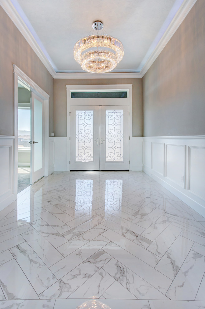Cette image montre une entrée traditionnelle de taille moyenne avec un couloir, un mur gris, un sol en marbre, une porte double, une porte blanche et un sol blanc.