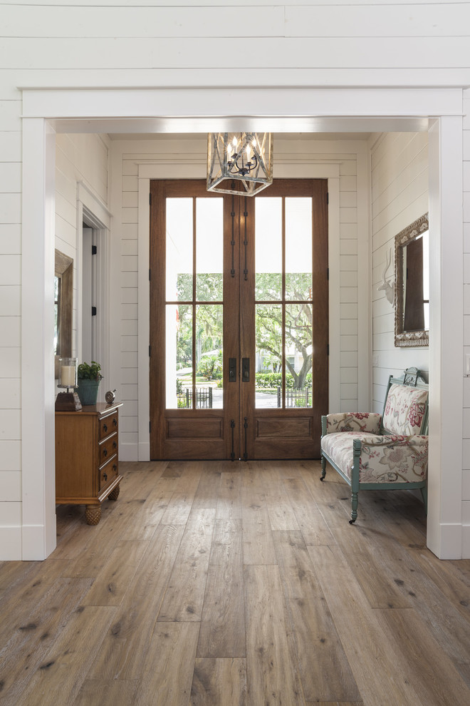 タンパにある広いラスティックスタイルのおしゃれな玄関 (淡色無垢フローリング、木目調のドア、茶色い床) の写真