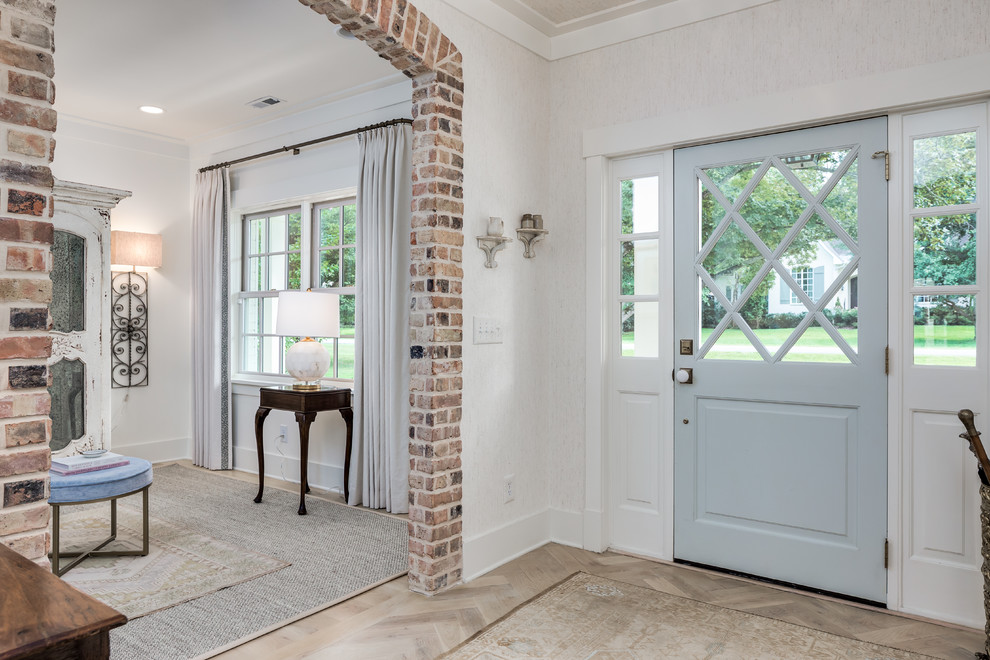 Cette image montre une petite porte d'entrée rustique avec un mur blanc, une porte simple, une porte bleue, parquet clair et un sol beige.