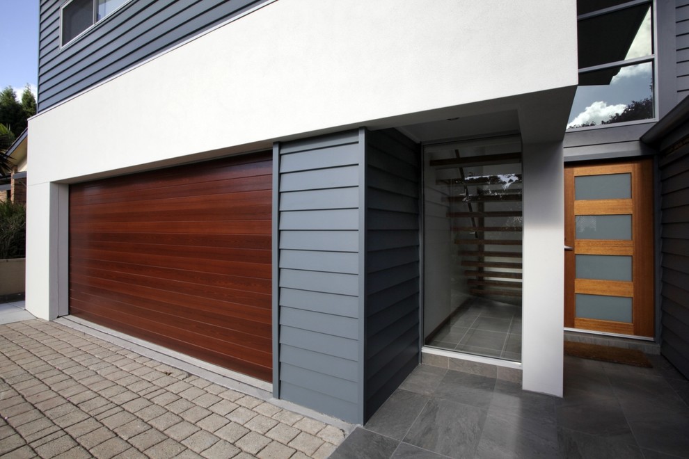 Example of a minimalist ceramic tile entryway design in Newcastle - Maitland with a medium wood front door