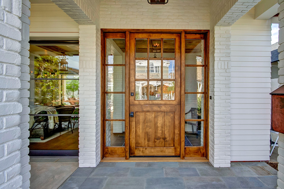 Immagine di una porta d'ingresso country di medie dimensioni con pareti bianche, pavimento in ardesia, una porta olandese, una porta in legno bruno e pavimento grigio