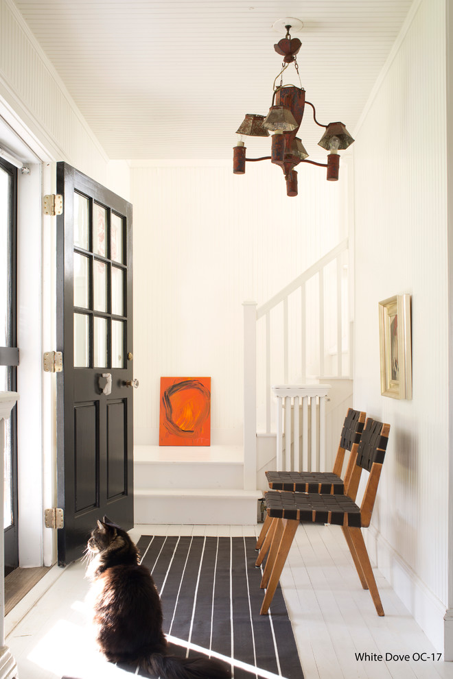 Idee per un ingresso tradizionale di medie dimensioni con pareti bianche, pavimento in legno verniciato, una porta singola e una porta nera