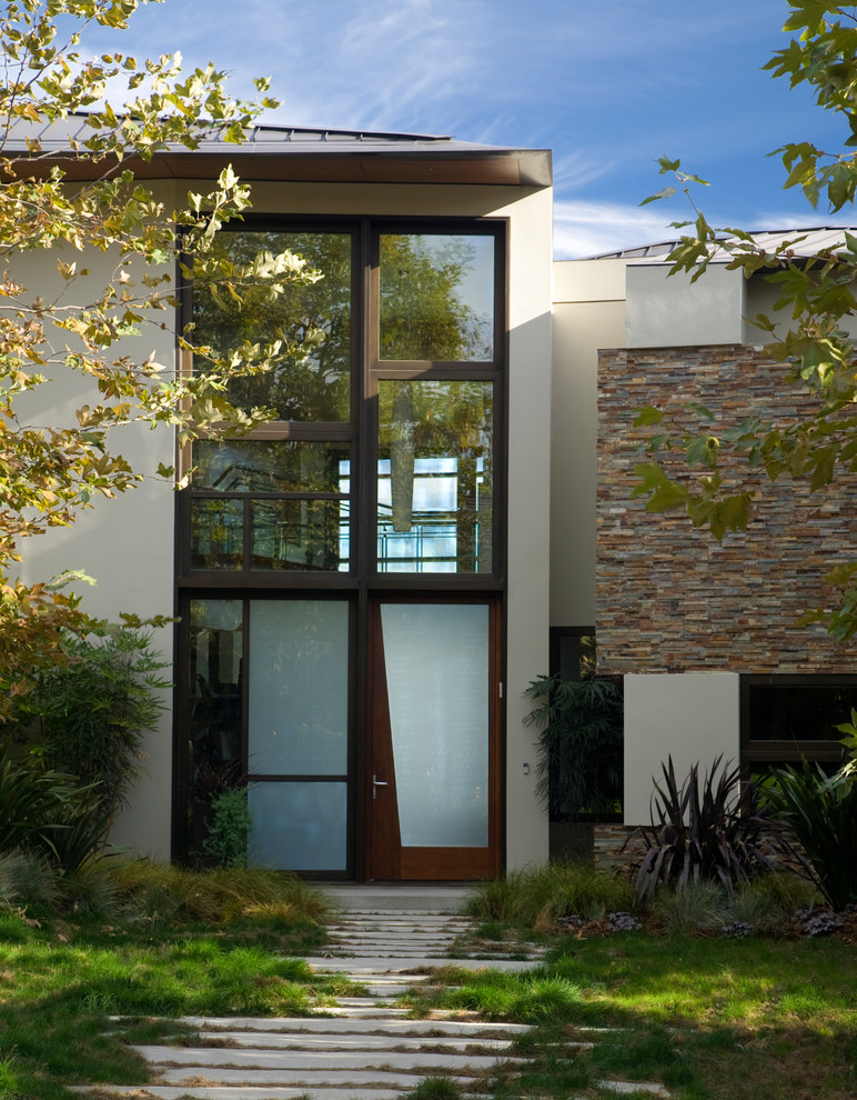 Modern inredning av en stor ingång och ytterdörr, med beige väggar, betonggolv, en enkeldörr och mörk trädörr