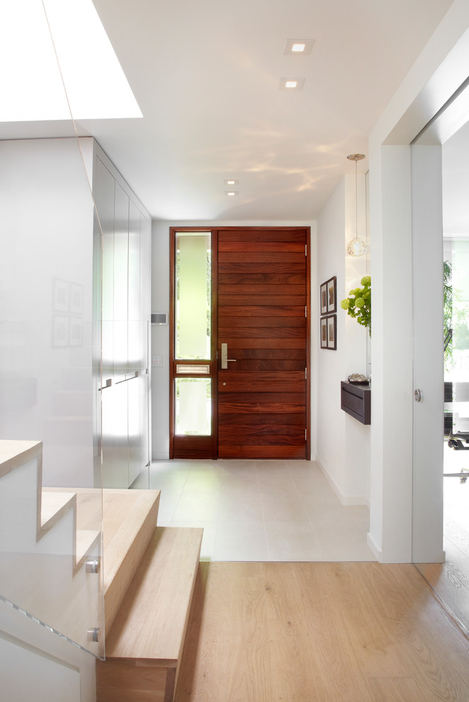 This is an example of a small contemporary hallway in Toronto with white walls, light hardwood flooring, a single front door and a medium wood front door.