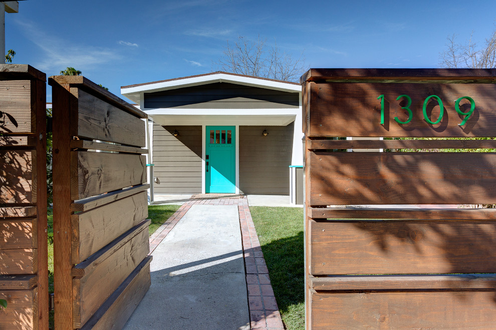 На фото: входная дверь среднего размера в современном стиле с коричневыми стенами, бетонным полом, одностворчатой входной дверью и синей входной дверью