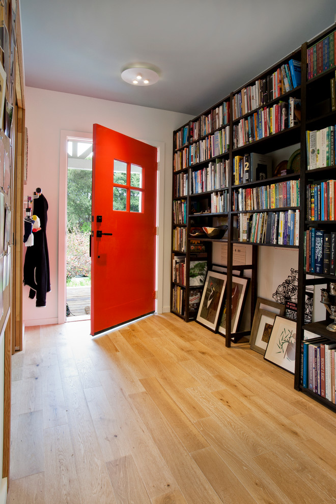 Cette image montre une petite entrée design avec un couloir, un mur blanc, parquet clair, une porte simple et une porte rouge.